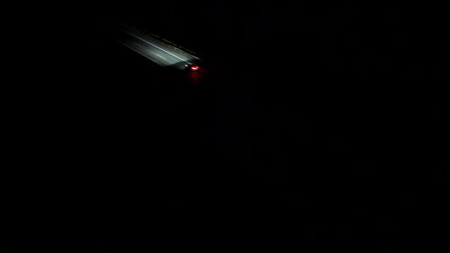 White xenon headlights and red backlights of cars or vehicles on motorway at night. Aerial top down shot. Traffic scene on American interstate highway.
