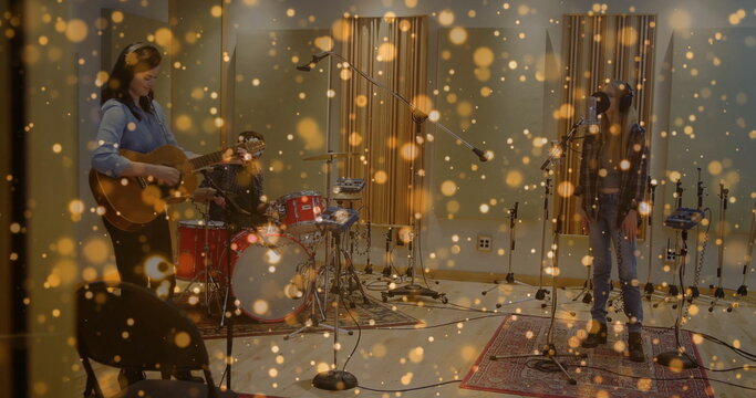 Three musicians jamming together in recording studio, with acoustic guitar and drum kit
