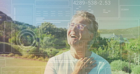Smiling senior man wearing glasses and t-shirt in rural vineyard hills, with digital charts overlay