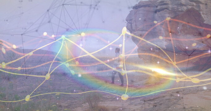 Walking man wearing baseball cap crossing desert toward sandstone outcrop, with network overlay