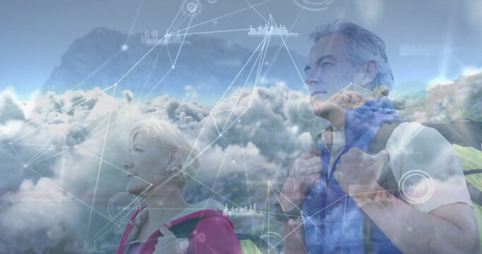 Standing senior couple gazing skyward on mountain ridge, carrying hiking packs with digital overlay