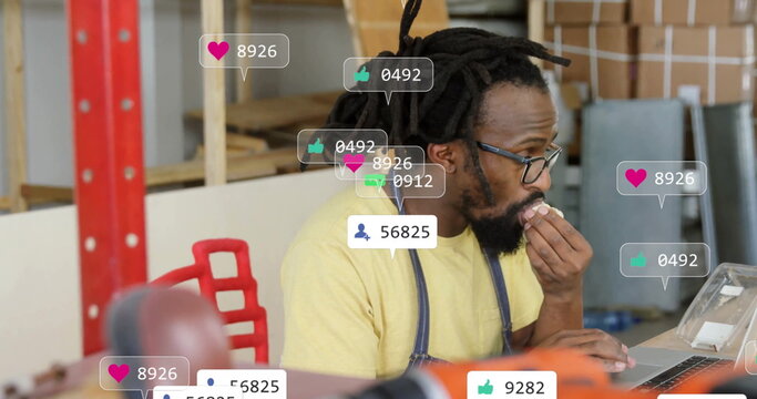 Monitoring social icons, dreadlocked man using laptop at workshop, holding snack by power drill