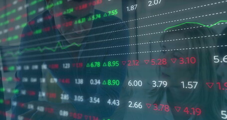 Analyzing colleagues in suits examining digital display in office, with stock market data overlays