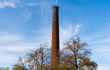Chimney tower or industrial smokestack. Tower from red brick. Industrial architecture of chimney tower. Brick factory chimney tube. Industrial brick chimney at factory