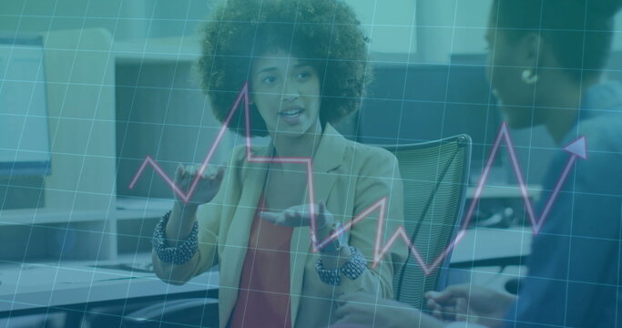 Gesturing woman in beige blazer and red blouse analyzing data, with overlaid line graph in office