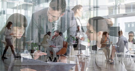 Chatting man in suit and woman in blazer sitting in office lounge, with orange chairs