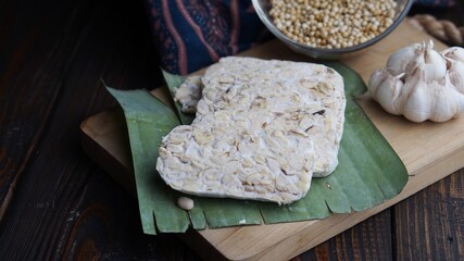 Raw tempe or tempe mentah. Tempeh slices in wooden plate. Tempe is Fermented Soy Product Originally from Indonesia. Asian food.