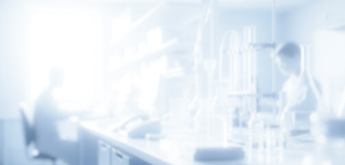 Blurred image of people working in a bright white laboratory environment, reflecting modern scientific collaboration with advanced equipment and clean professional workspace.