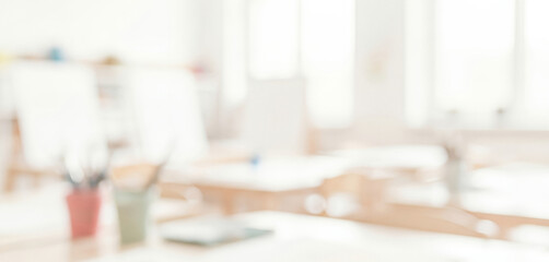 Blurred office space with desk computer and stationery in bright light, reflecting a classroom-style workspace with organized materials, modern equipment, and bright focused learning