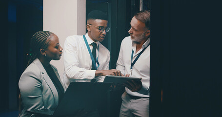 People, programming or tablet in server room, conversation or teamwork with engineering. IT specialist, technical support or employees with discussion, problem solving or feedback with cyber security