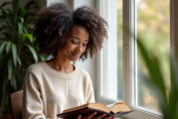 Young African American Woman Reading Open Bible by Window in Soft Natural Light