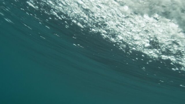 Slow motion of underside of ocean wave, smooth textures and filtered light from below