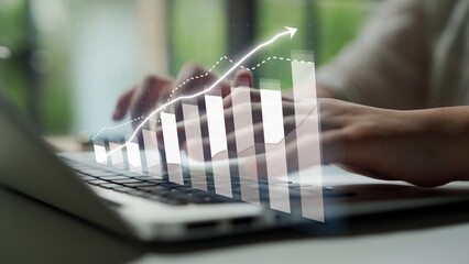 Close-up view of hands typing on a laptop, with an overlay of a graph depicting growth, symbolizing success and digital analysis in a modern workspace. Copula