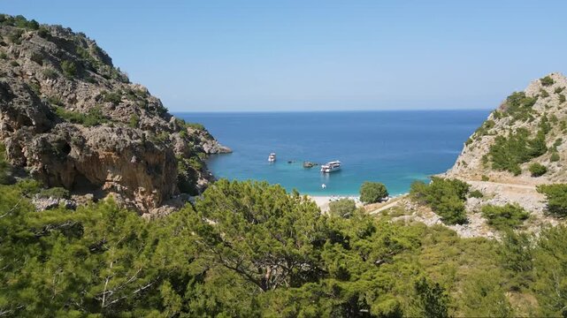 Drone footage revealing Achata Beach in Karpathos, hidden behind lush green pine trees, with turquoise waters and a scenic Mediterranean coastline.