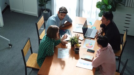 Skilled project manager walking at table while colleague brainstorm idea. Business team working together to plan marketing strategy while looking at data analysis or financial statistic. Convocation.