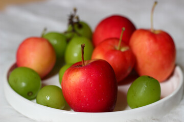 Fresh red apples and palm fruits on a white plate. Organic tropical fruits perfect for healthy eating, nutrition, and food photography.