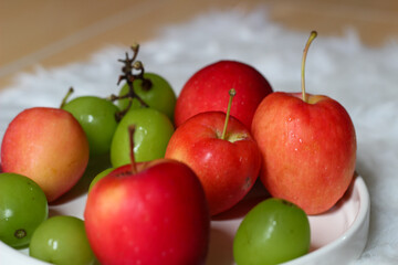 Fresh red apples and palm fruits on a white plate. Organic tropical fruits perfect for healthy eating, nutrition, and food photography.