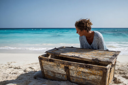 Woman looking inside treasure chest on deserted beach