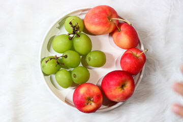 Fresh red apples and palm fruits on a white plate. Organic tropical fruits perfect for healthy eating, nutrition, and food photography.