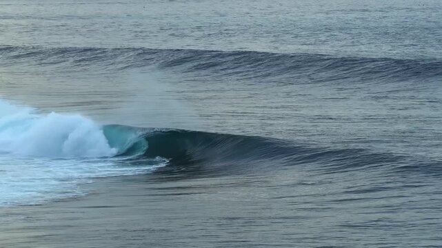 Cinematic drone footage of a grinding left-hander at Nusa Lembongan, Bali. The reef break spits twice in a dramatic display of wave power, filmed in golden tropical light.