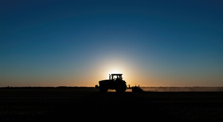Silhouette of a tractor plowing a field at sunset, agriculture industry.