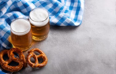 Two glasses of beer and pretzels with blue checkered tablecloth on gray background celebrating oktoberfest