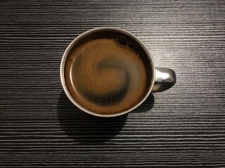Top view of a cup of black coffee on a dark wooden table