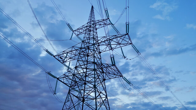 Towering electricity pylon with intricate lattice structure and high-voltage power lines against a dramatic sky, symbolizing sustainable energy infrastructure and modern power distribution.