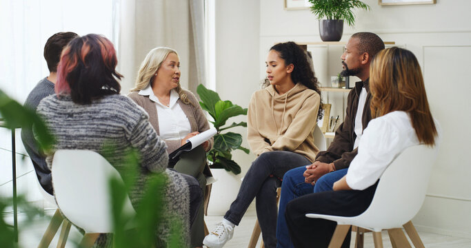 Therapist, counseling and group of people in office with support, help or mental health development. Communication, men and women in meeting with psychologist, discussion or listening to advice.