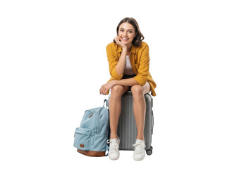 Young woman traveler with suitcase and backpack sitting and smiling, isolated on transparent background