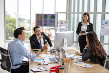 Female executive presents to her team in a contemporary office setting, where an asian businesswoman guides colleagues through strategic planning and business discussion, representing corporate leader