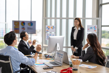 Female executive presents to her team in a contemporary office setting, where an asian businesswoman guides colleagues through strategic planning and business discussion, representing corporate leader