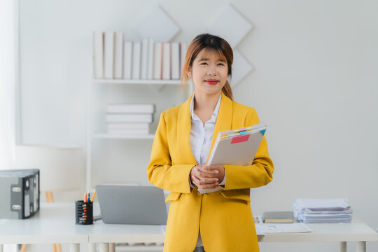 Confident Professional Portrait: A poised woman in a smart blazer, exuding professionalism and assurance, stands ready for business in her office. 