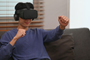Asian teenage boy using a VR headset with headphones, immersed in a virtual gaming experience