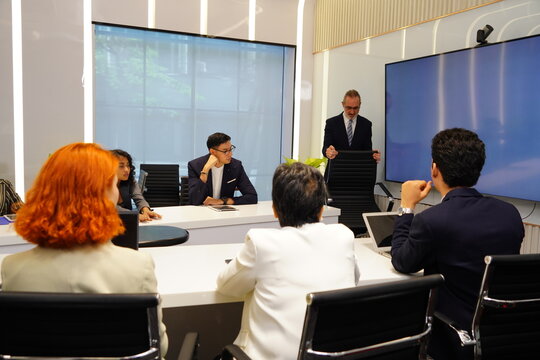 Businessman and female staff standing presenting data graph, marketing information, sales progress and performance report summary to meeting in conference room. Business concept.
