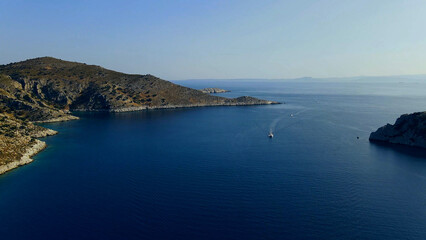 Bird's eye view of a lonely yacht sailing on calm water in a picturesque sea bay © AnyVIDStudio