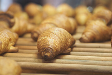 Croissants arranged on wooden display in bakery shop