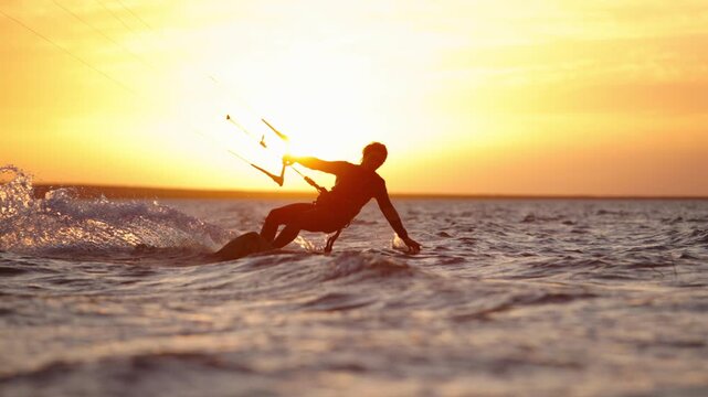 Slow motion kitesurfer carving wave with spray at golden hour sunset showing extreme water sport adrenaline dynamic movement action lifestyle strength performance and breathtaking athletic freedom