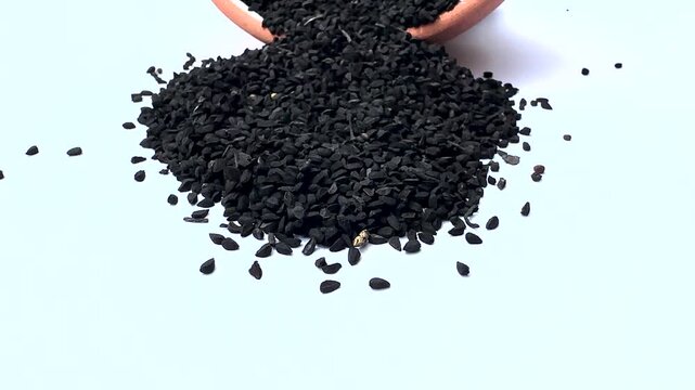 Black Cumin Spilled from Terracotta Bowl on White background