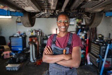 Confident African American Female Mechanic Smiling with Arms Crossed in Garage