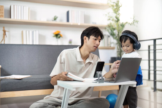 Family Time. Young man engaging with child while working on laptop.