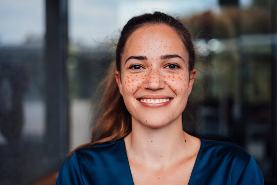 Happy young businesswoman with dots marking on face