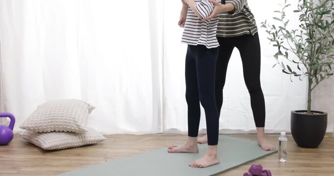 A mother is training her daughter, A mother guides her cheerful daughter through a stretching routine at home, exercising for a healthy lifestyle concept