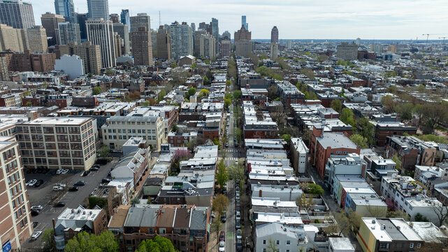 Aerial view of streets lined with dense buildings leading to distant skyscrapers under a muted sky, Philadelphia, Pennsylvania, United States.