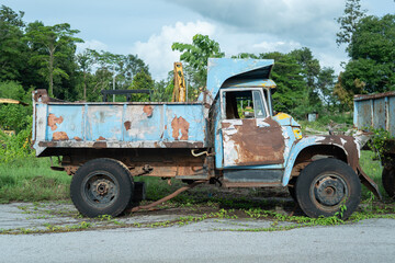 Obraz premium Abandoned Truck: An old, weathered truck, bearing the marks of time and rust, sits stationary amidst a backdrop of lush greenery, its history etched into its worn surfaces.