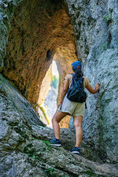 Woman hiking in natural rock arch at Vratna caves, Serbia