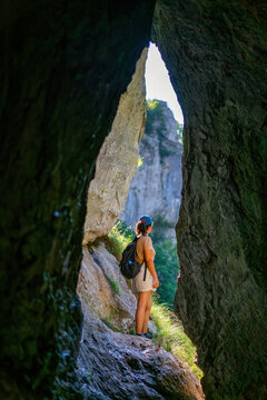 Woman hiking in natural rock arch at Vratna caves, Serbia
