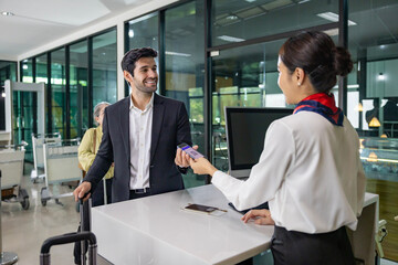 Fototapeta premium Caucasian businessman passenger is receiving boarding pass from the airline ground crew at check in counter at departure terminal into the airplane for final inspection before boarding to plane