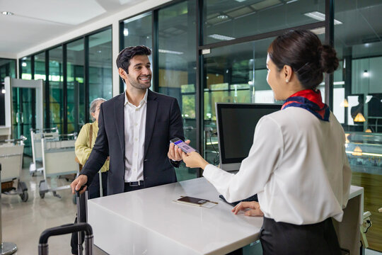 Caucasian businessman passenger is receiving boarding pass from the airline ground crew at check in counter at departure terminal into the airplane for final inspection before boarding to plane