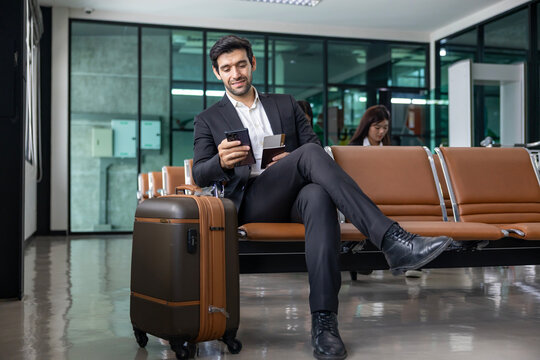 Caucasian businessman is using smart mobile phone while waiting in airline business departure lounge waiting for boarding airplane